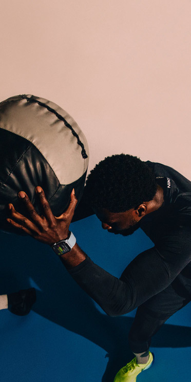 Un homme portant une Apple Watch Series 10 tient une medicine-ball pendant un entraînement.