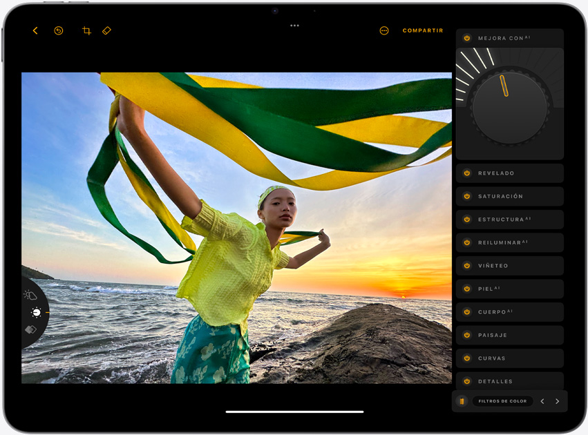 iPad Air, posición horizontal, muestra la foto de una chica que sostiene unas cintas amarillas y verdes con un atardecer en el mar de fondo