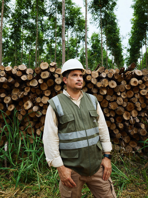 Alvaro Ramirez se tient devant une pile de rondins de bois.