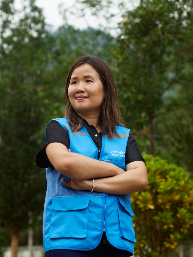 Una foto di Chu Thanh Hoa che si trova in piedi, all’aperto, e indossa un gilet blu di Gravity Water.