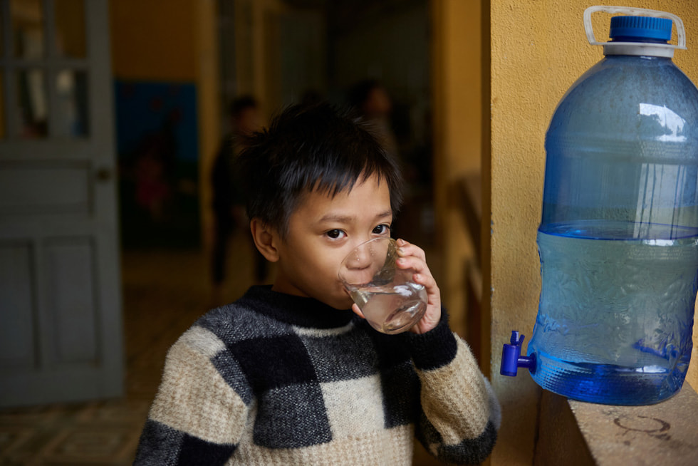 A student is shown drinking water procured from the Gravity Water system at the Vầy Nưa Primary and Secondary Boarding School for Ethnic Minorities.