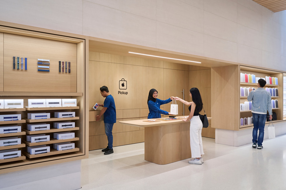 Två medarbetare hjälper en kund i Apples hämtningsavdelning inne i Apple The Exchange TRX.