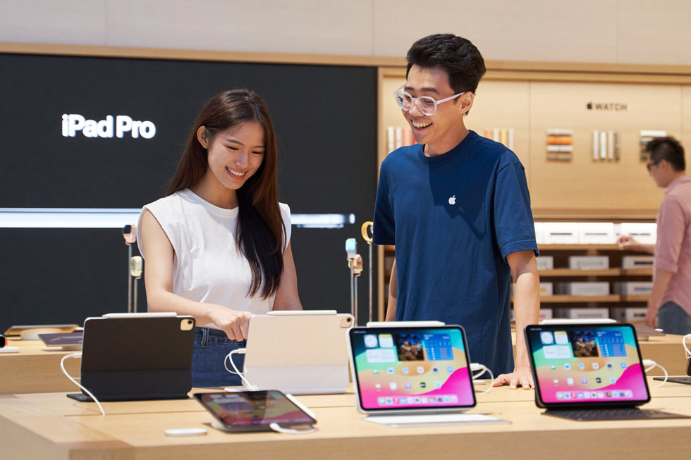 Une cliente et un membre de l’équipe Apple se tiennent debout devant la gamme d’iPad. 