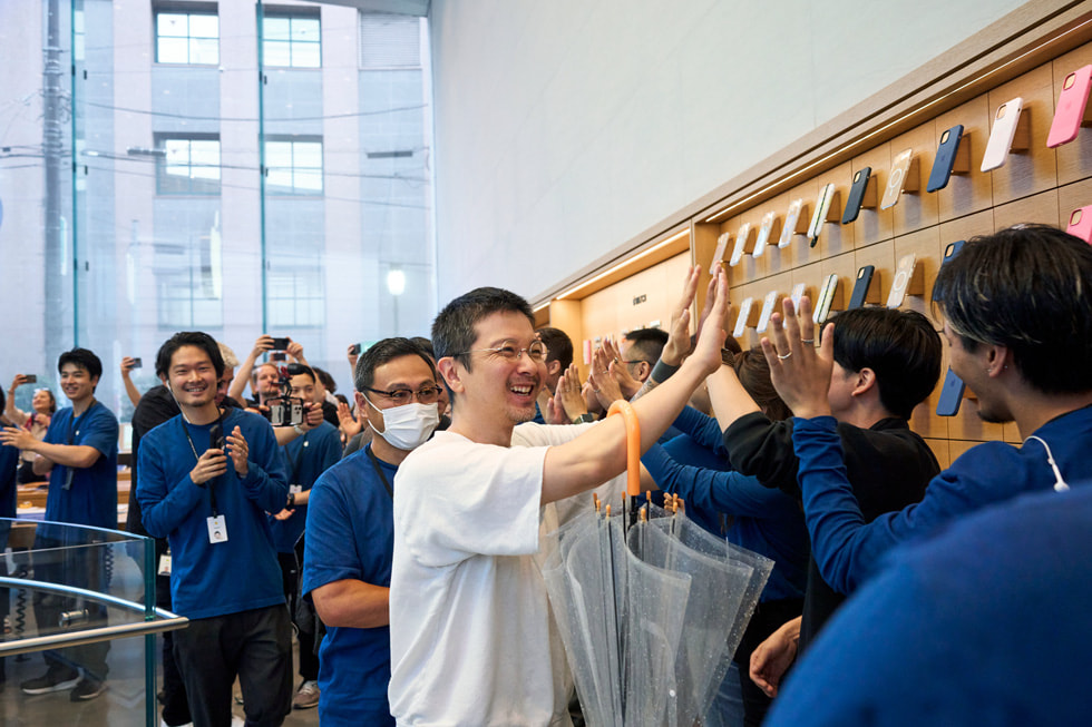 A customer high-fives a line of Apple team members inside Apple Omotesando.
