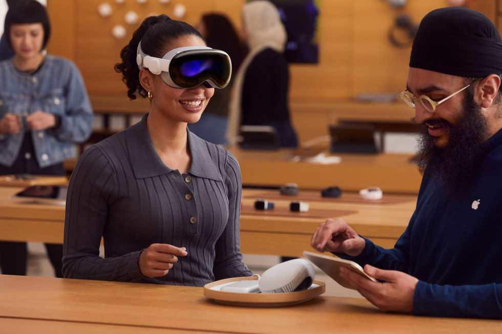 A customer trying out Apple Vision Pro in an Apple Store is shown.