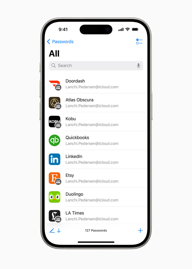 Un iPhone 15 Pro muestra la app Contraseñas con una lista de iconos de apps, entre ellas Door Dash, Atlas Obscura y LinkedIn.
