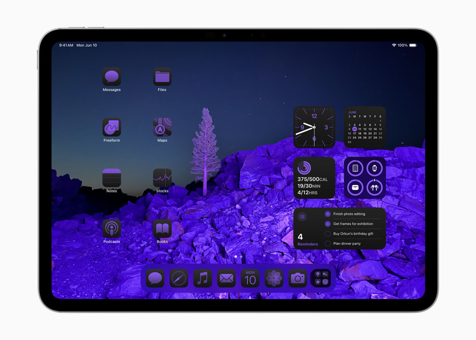 Een iPad Pro met appsymbolen en widgets in een paars kleurenschema rondom een achtergrondafbeelding van een landschap. 