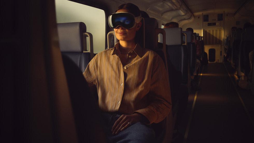 Podróżująca pociągiem osoba z założonym urządzeniem Apple Vision Pro.