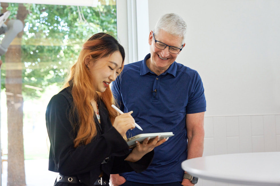 صورة لتيم كوك مع طالبة مطورة تحمل جهاز iPad وقلم Apple.