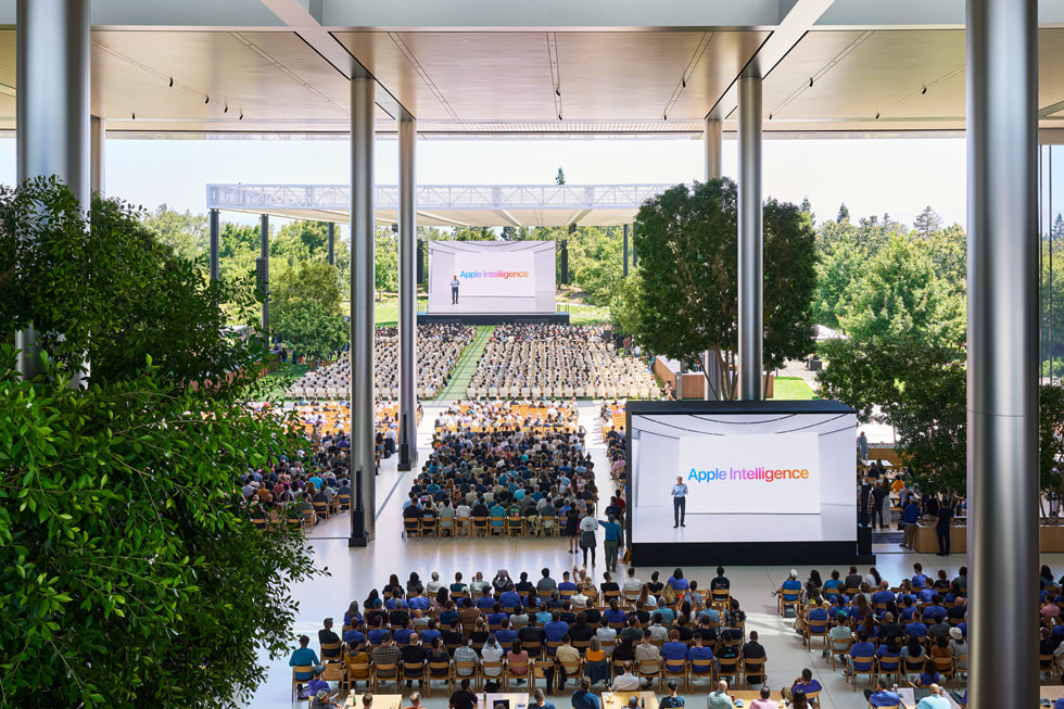 Apple Park의 Caffè Macs에서 큰 화면으로 키노트 발표를 시청 중인 개발자들의 모습을 오버헤드 샷으로 촬영한 이미지. 