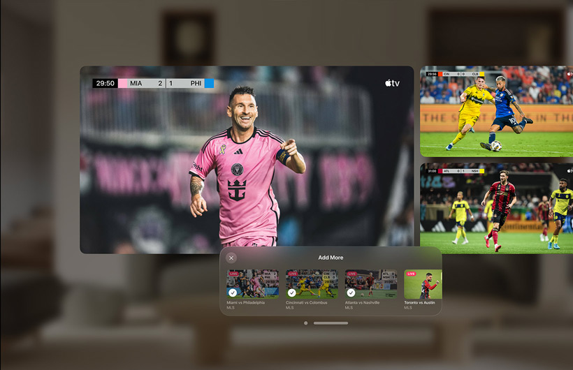 A man wearing Apple Vision Pro is sitting on a sofa in a living room. Displayed in front of him are a large video screen alongside two smaller screens, each showing a different sporting event. Below the large screen is selection window that reads “Add More” along the top