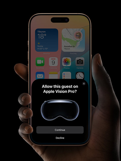 A hand holding an iPhone. The iPhone’s screen displays a window with the message “Allow this guest on Apple Vision Pro?” with buttons labelled “Continue” and “Decline”.